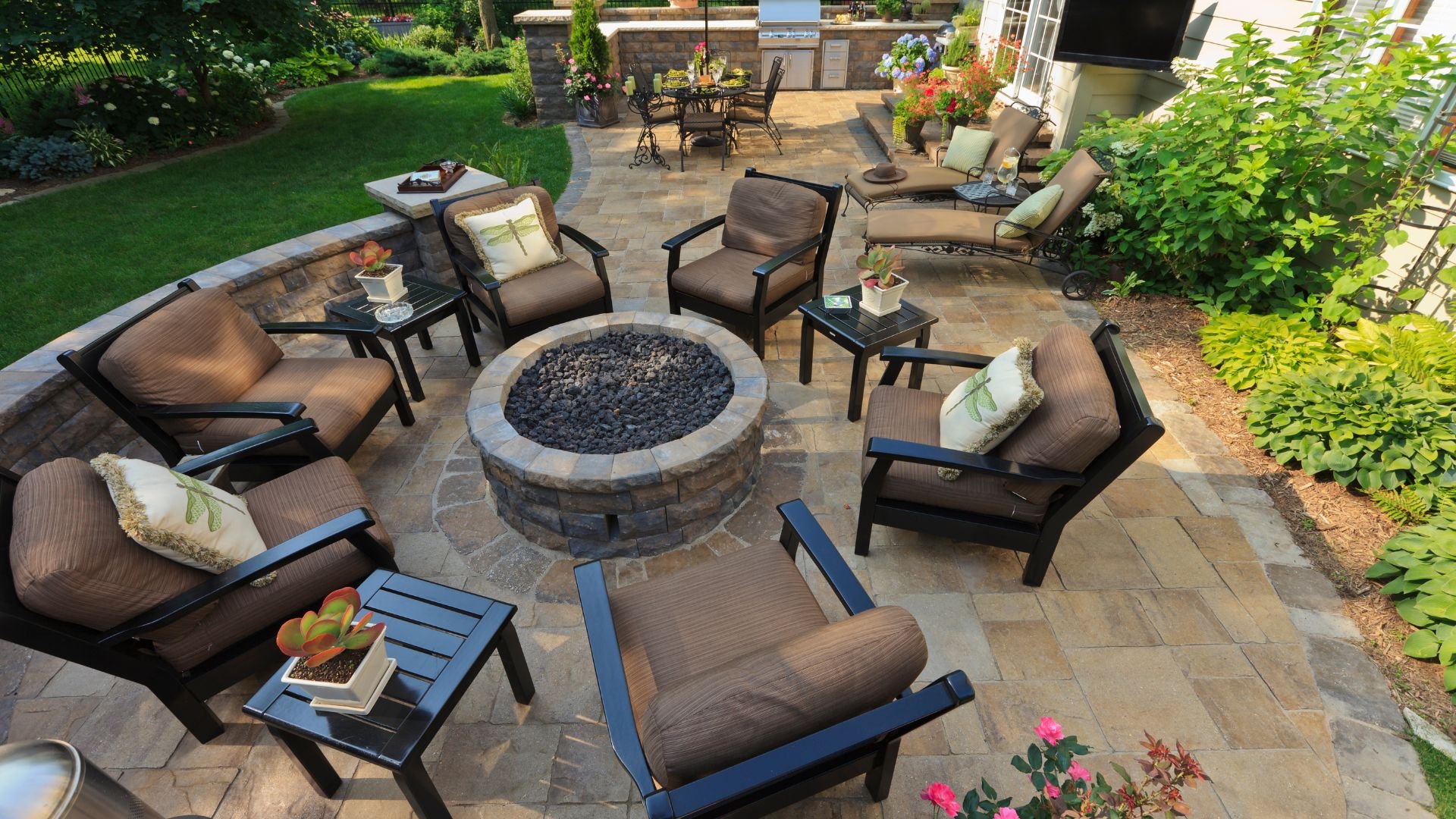 Luxurious outdoor patio with fire pit, lounge chairs, and stone landscaping