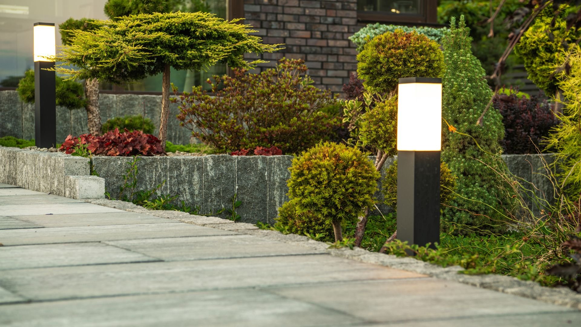 Well-manicured garden with stone pathway, topiary, and illuminated landscape lights