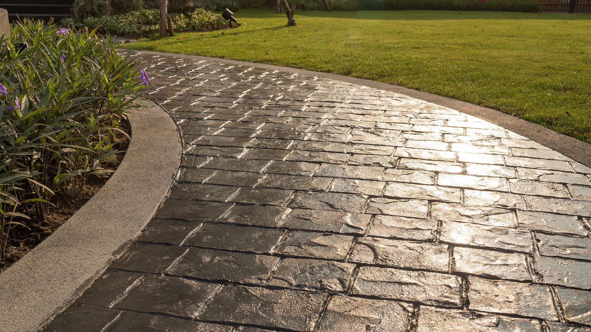 Curved stone walkway with sunlight reflecting on textured pavers