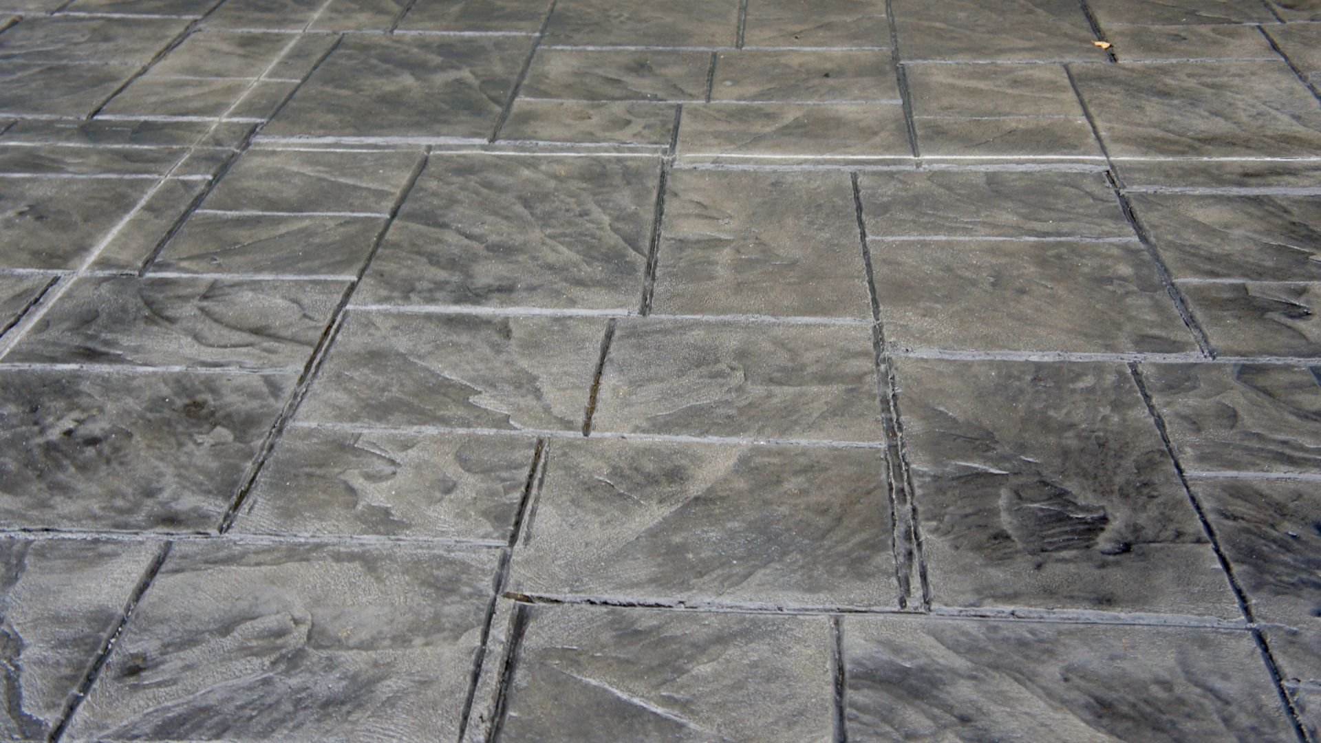 Textured gray concrete patio with stamped stone-like pattern and grout lines