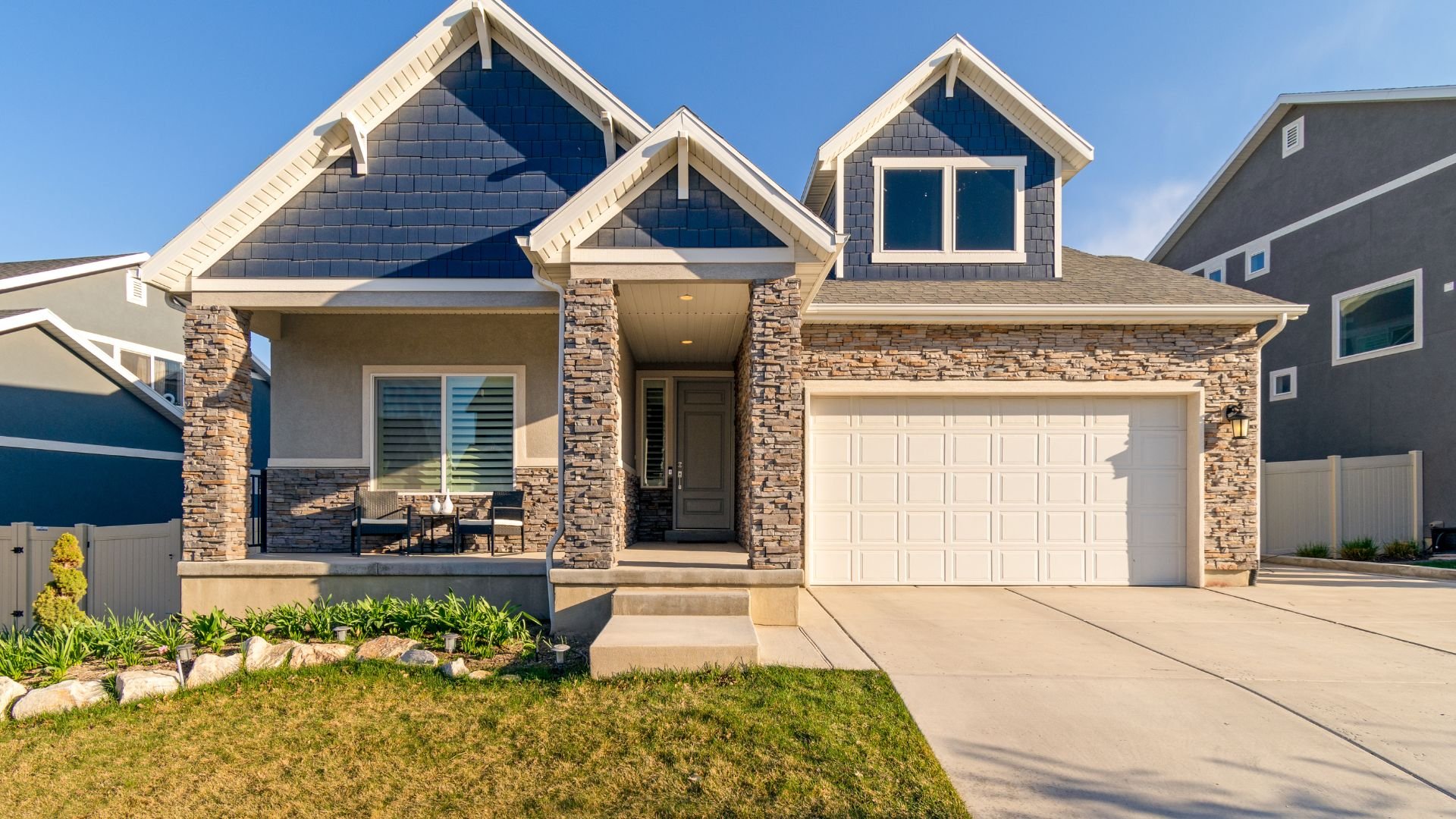 Modern stone and blue-gray house with white garage and front porch